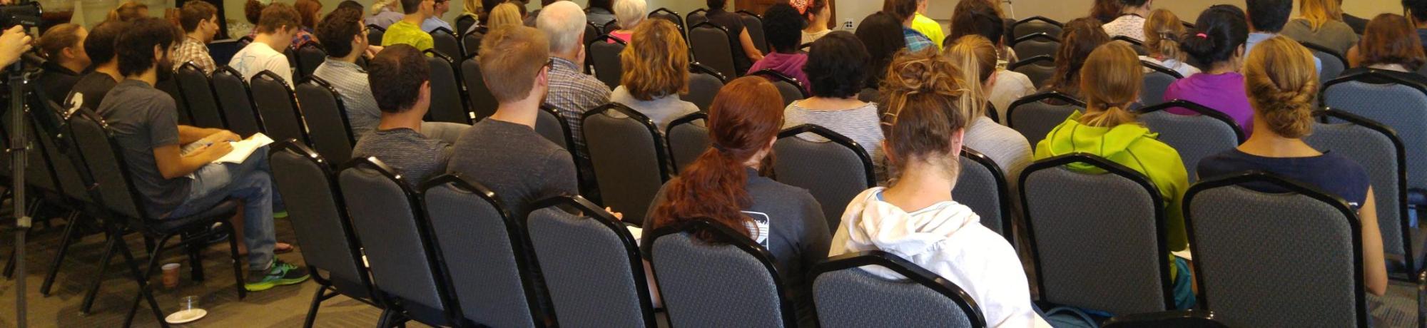 People sitting in chairs at an event.